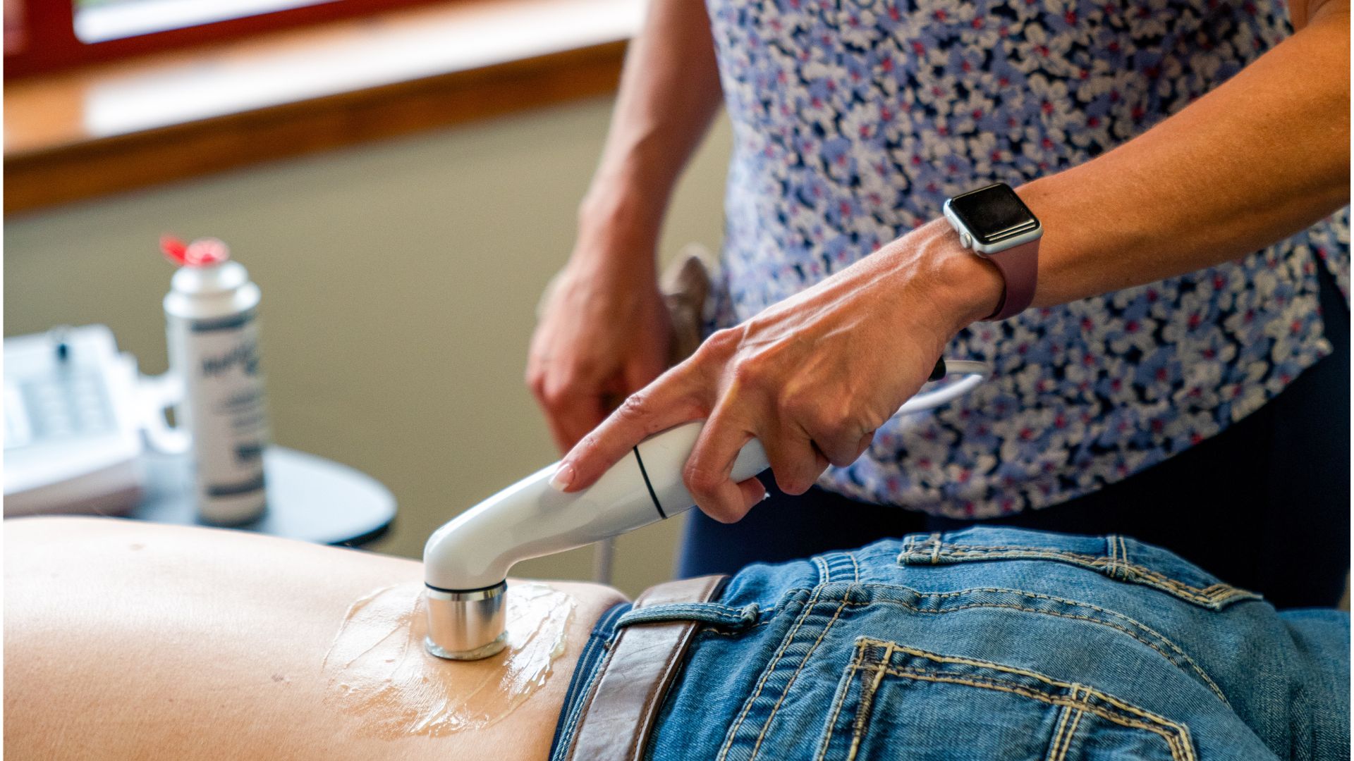 Patient lying face down on a treatment table while a Point Chiropractic provider applies therapeutic ultrasound to the lower back and hip