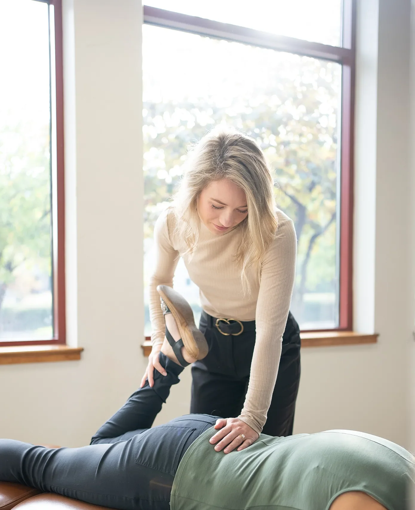 Chiropractor placing hands on a patient's lower back while the patient lies face down