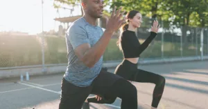 Two people working out together outside.